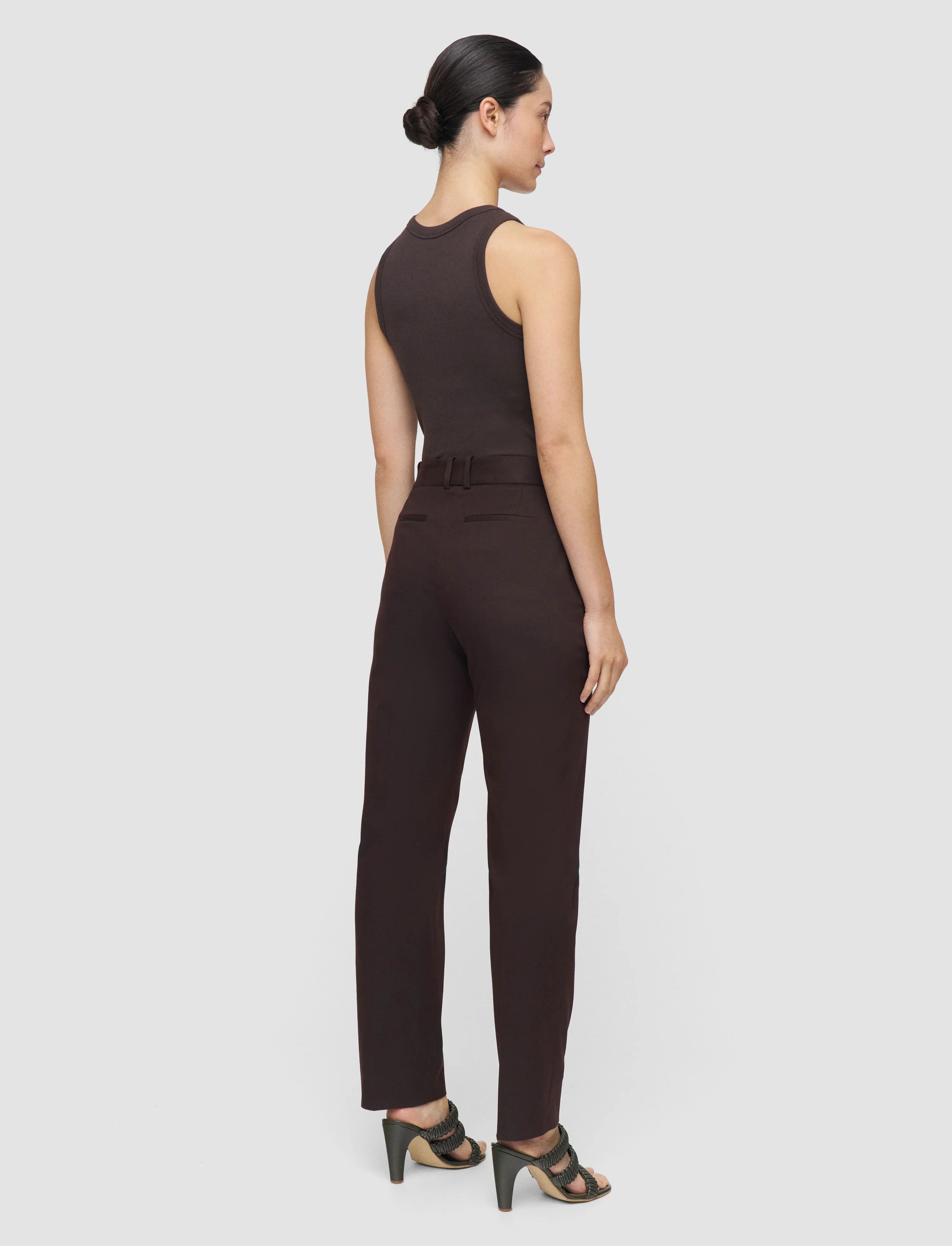 Woman wearing a brown jumpsuit on a light gray background