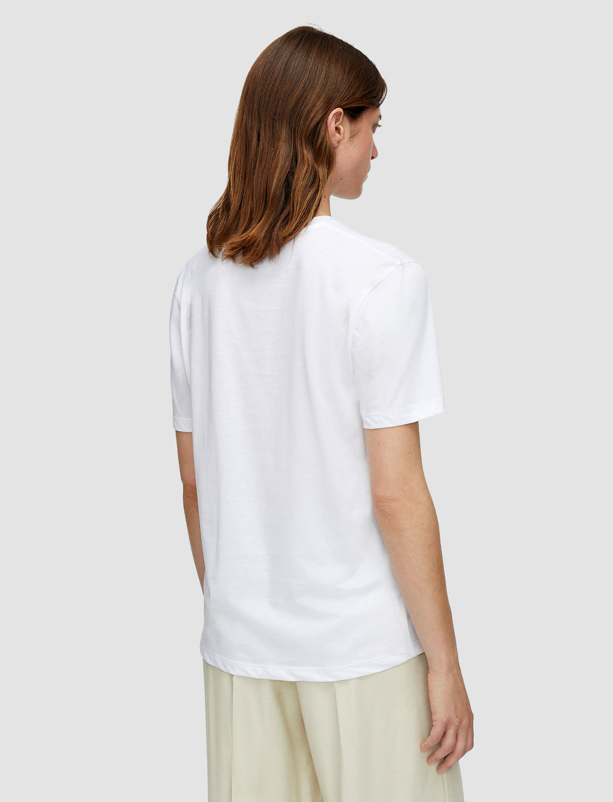 A woman with shoulder-length brown hair is shown from the back wearing a plain white short-sleeve t-shirt from Joseph. 