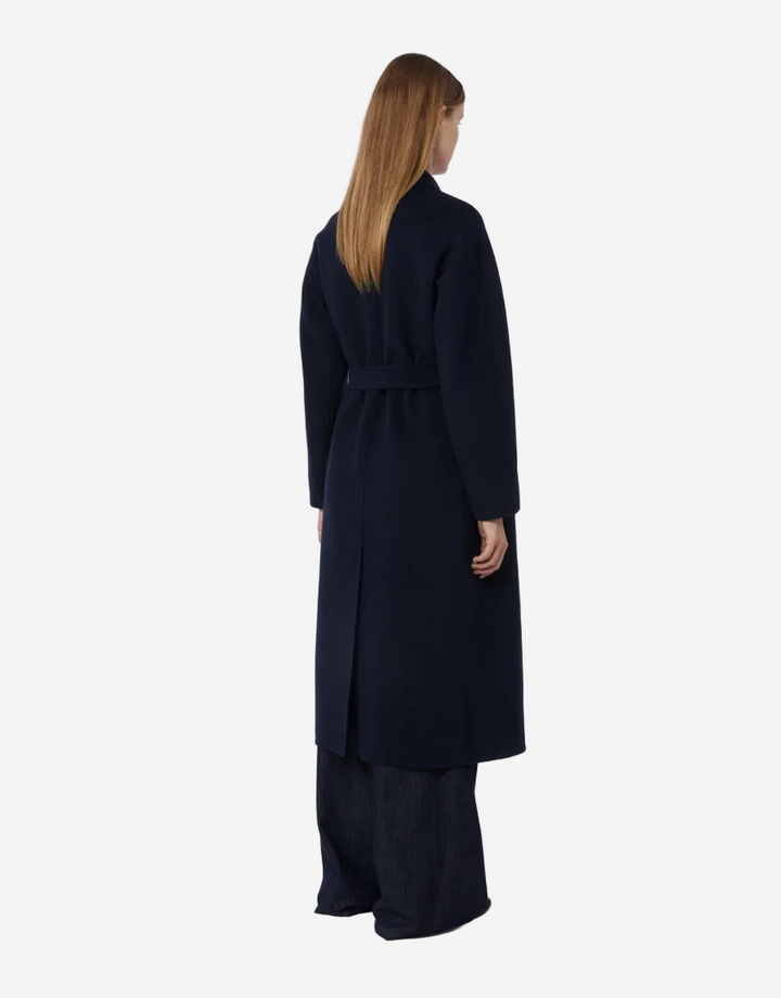 Woman wearing a long black coat on a white background