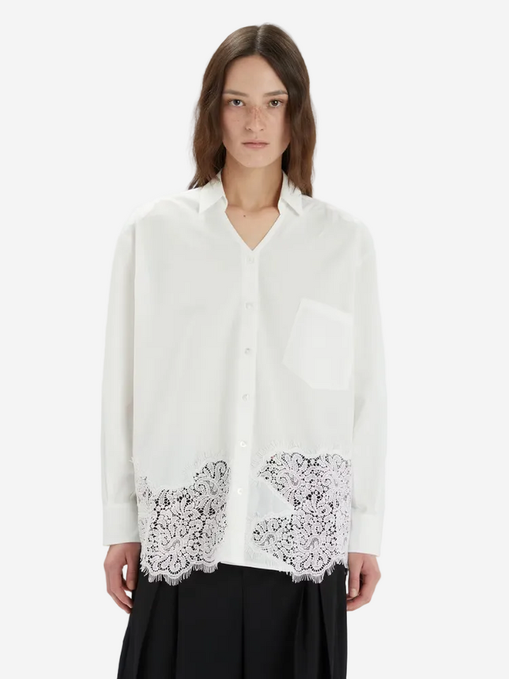 Woman wearing a white blouse with lace details on a white background