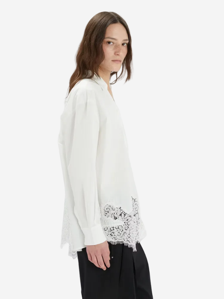 Woman wearing a white blouse with lace details on a white background