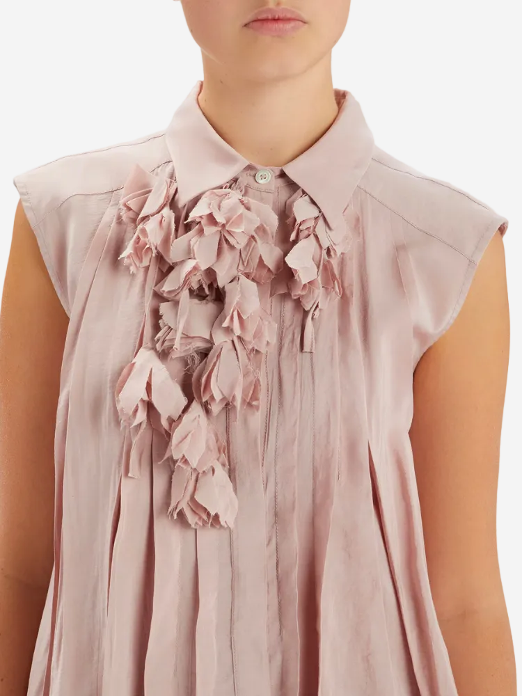 Pink blouse with floral details on a plain background
