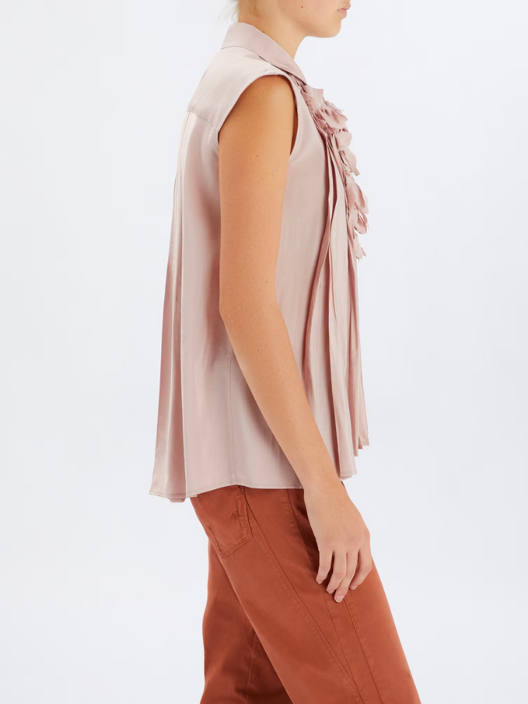 Woman wearing a sleeveless blouse with floral details on a white background
