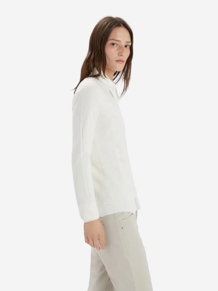 Person wearing a white sweater and light-colored pants on a plain background