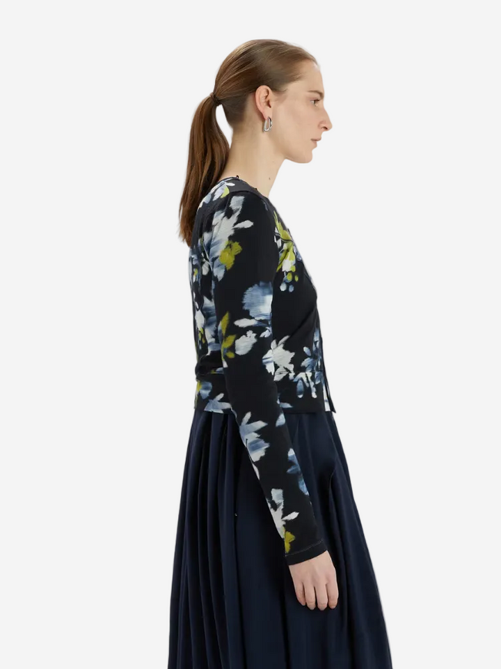 Woman wearing a black floral sweater with a plain background