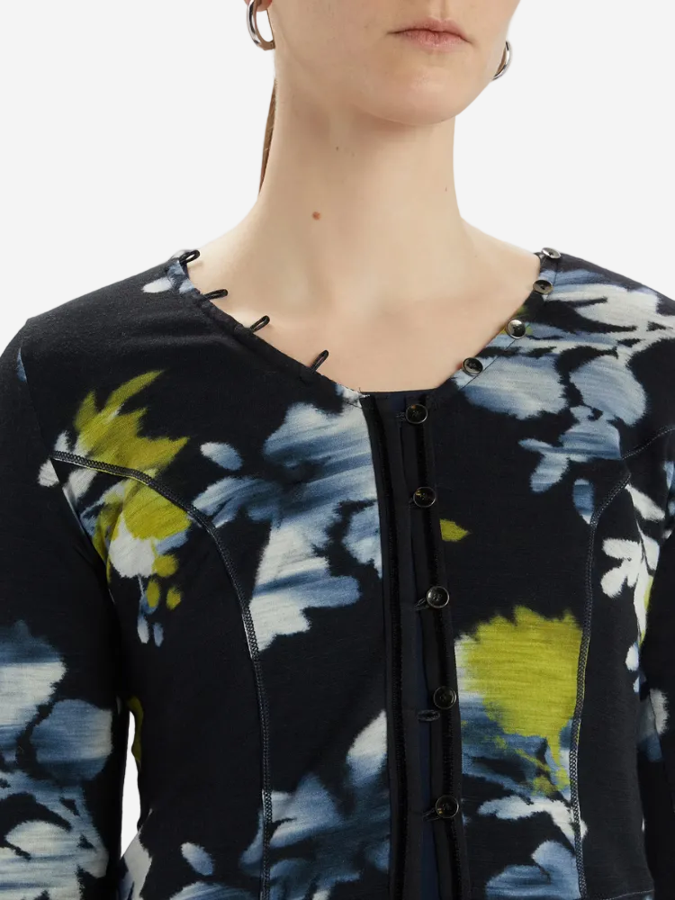 Close-up of a person wearing a black floral-patterned cardigan with yellow accents.