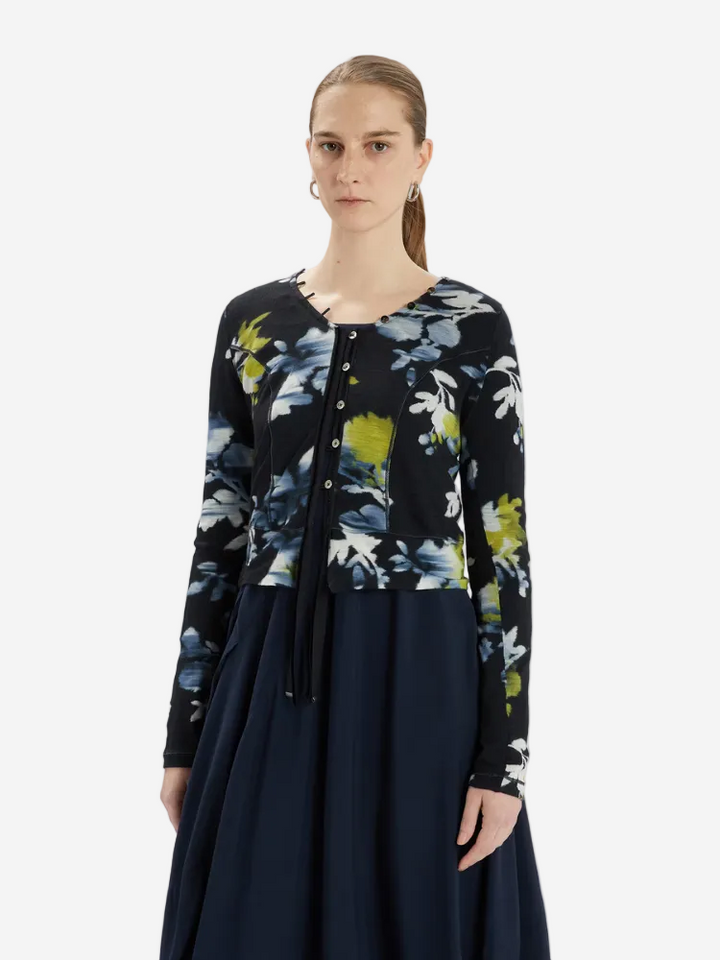 Woman wearing a black floral cardigan over a navy dress on a white background