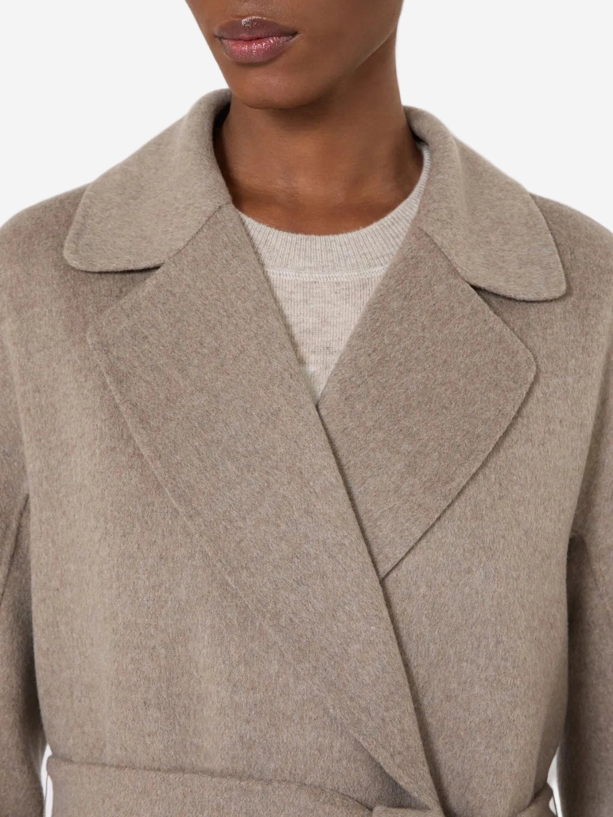 Close-up of a person wearing a beige coat with a neutral background