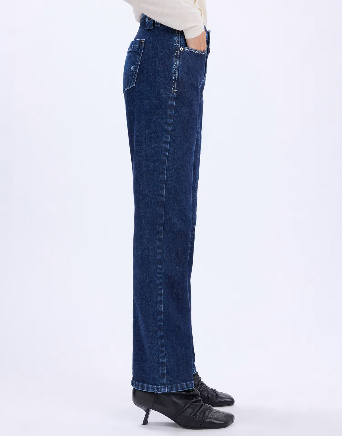 Side view of the HIGH Fairness jeans showing the straight leg and full-length hem, styled with black heels