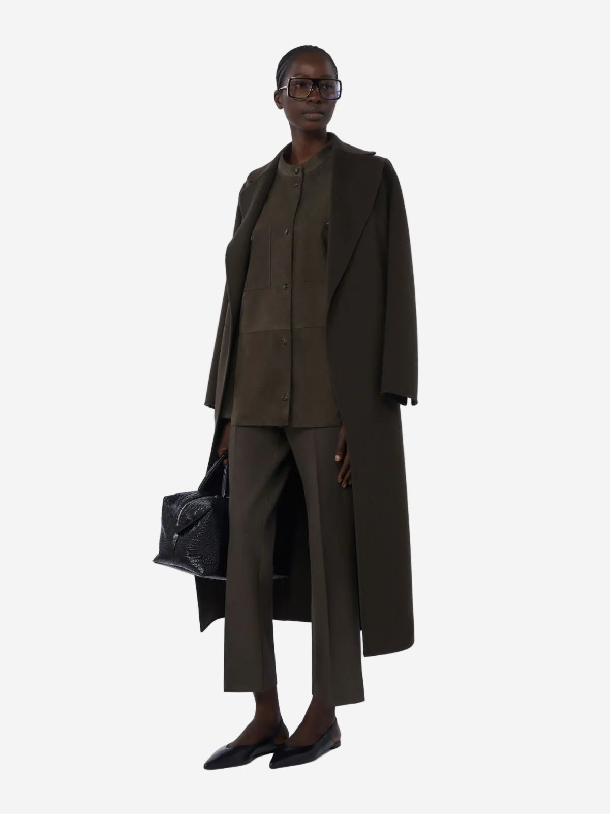 Person wearing a long dark green coat and pants on a white background