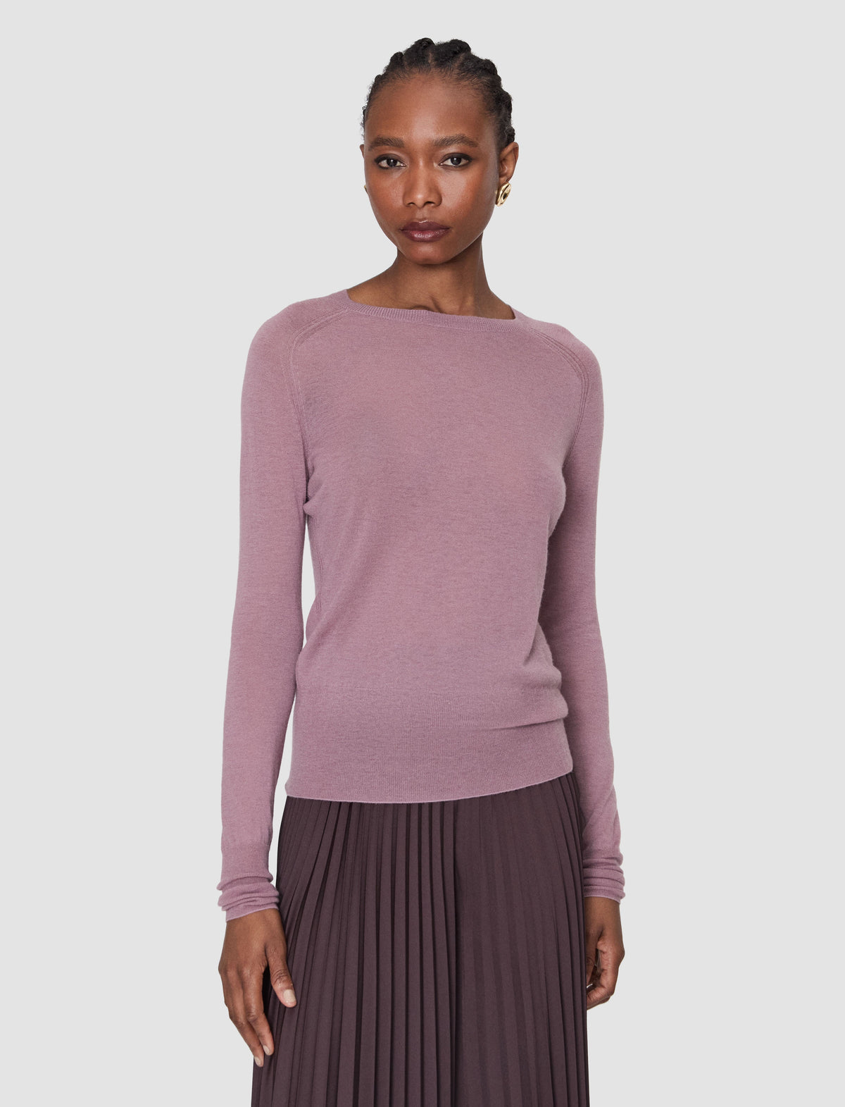 A woman modeling a dusty lilac long-sleeve knit top with a wide boat neckline from Christensen Copenhagen.