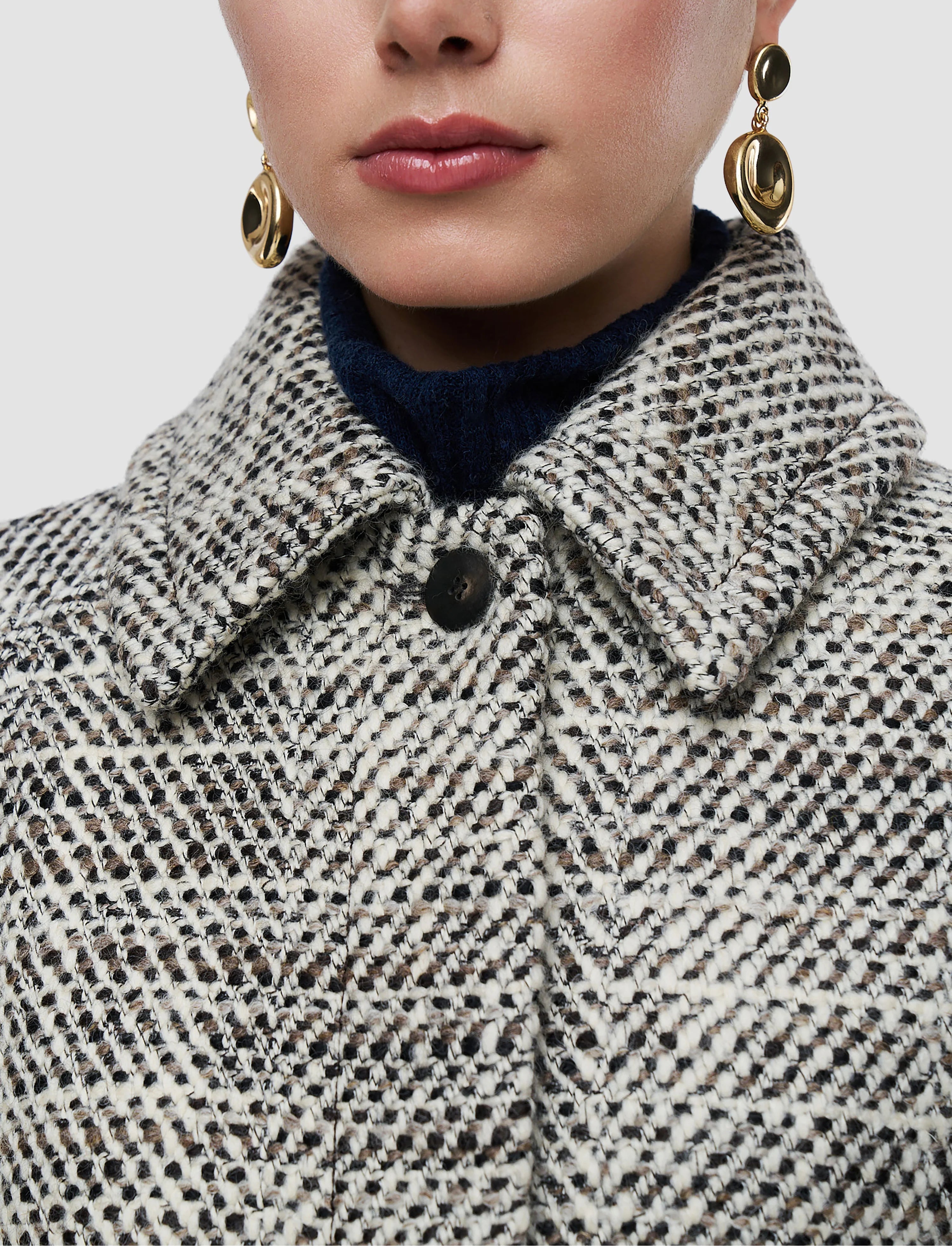 Close-up of a person wearing a patterned coat with a neutral background