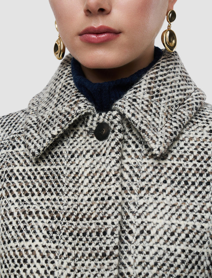 Close-up of a person wearing a patterned coat with a neutral background