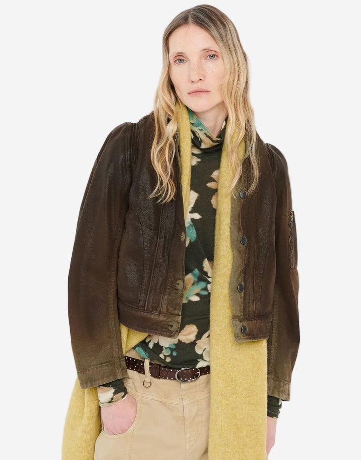 Woman wearing a brown jacket, floral shirt, and beige pants on a white background