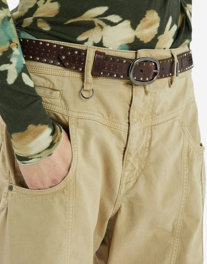 Close-up of beige pants with a brown belt and floral shirt sleeve.