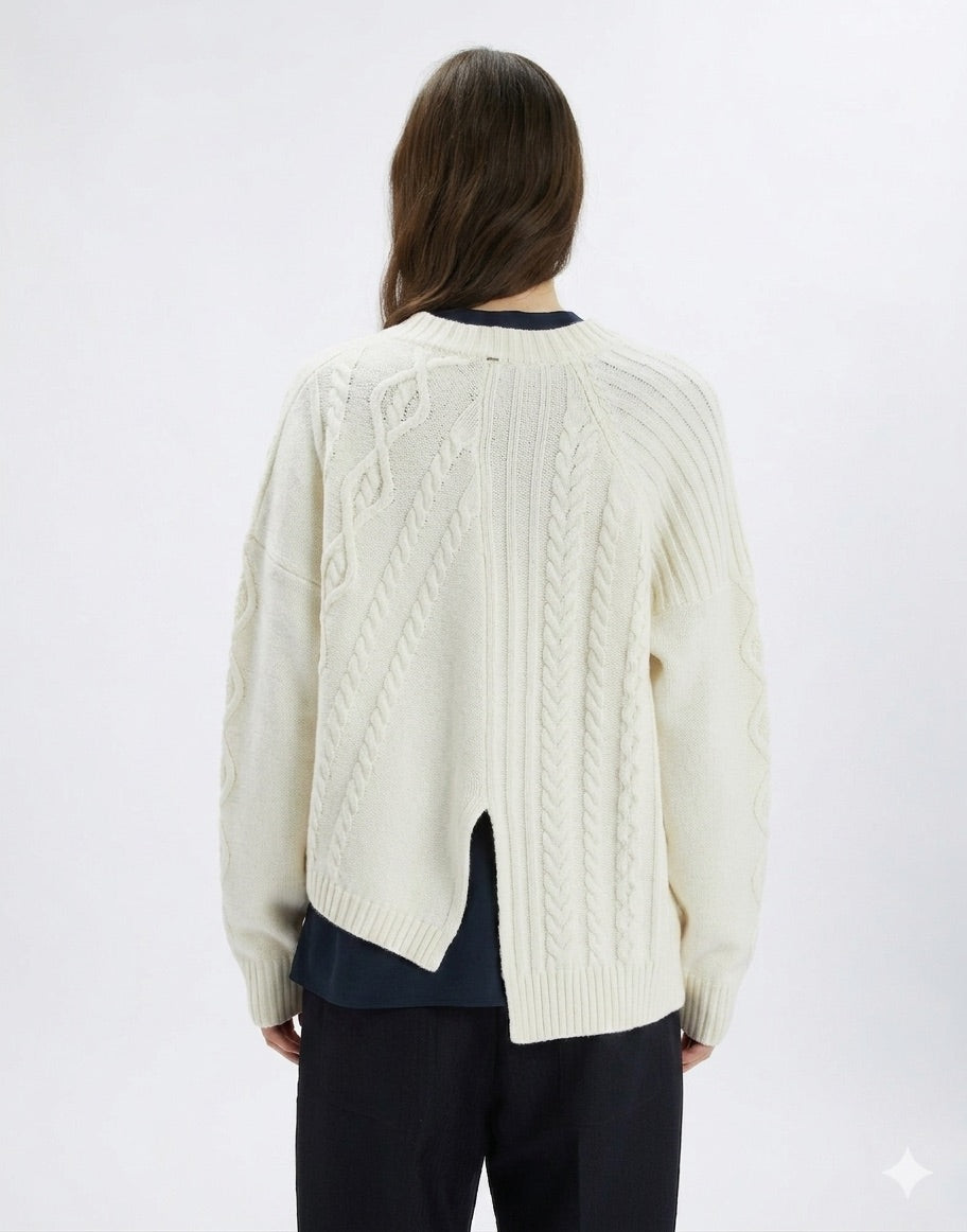 Person wearing a cream cable knit cardigan on a white background