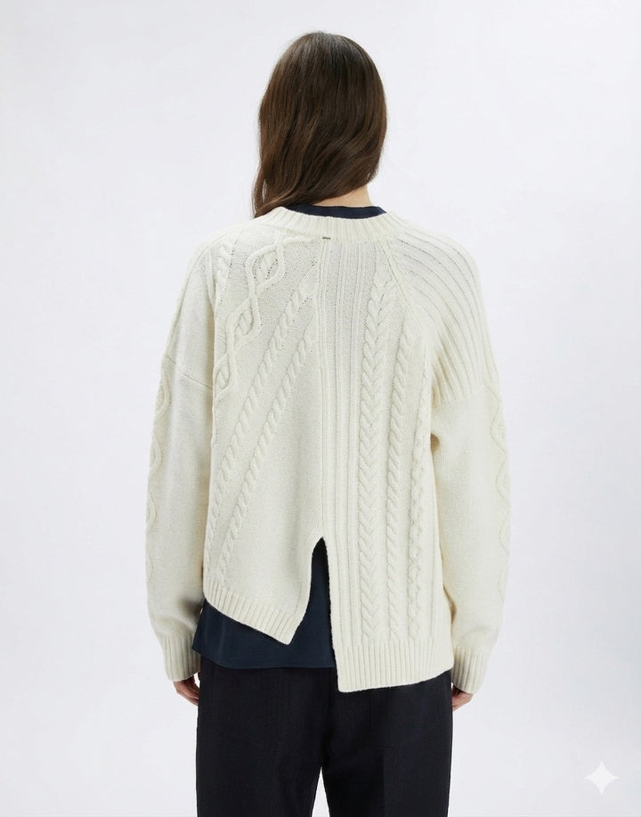 Person wearing a cream cable knit cardigan on a white background