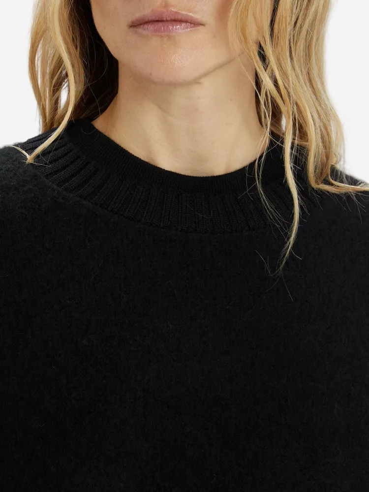 Close-up of a person wearing a black sweater with a blurred background