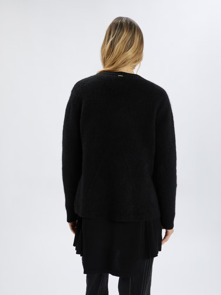 Person wearing a black sweater and skirt set on a white background