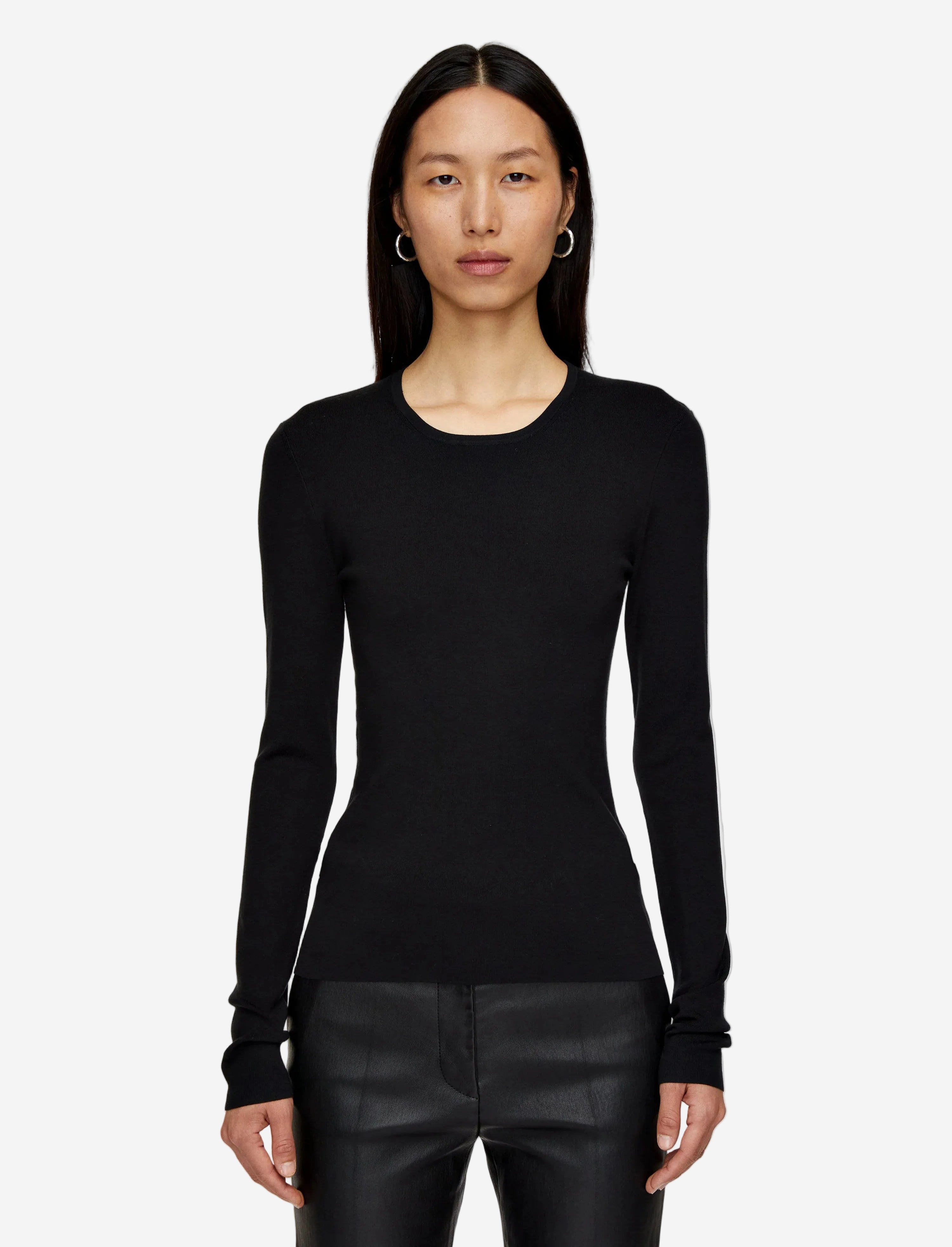 Woman wearing a black long-sleeve top and black pants on a light gray background