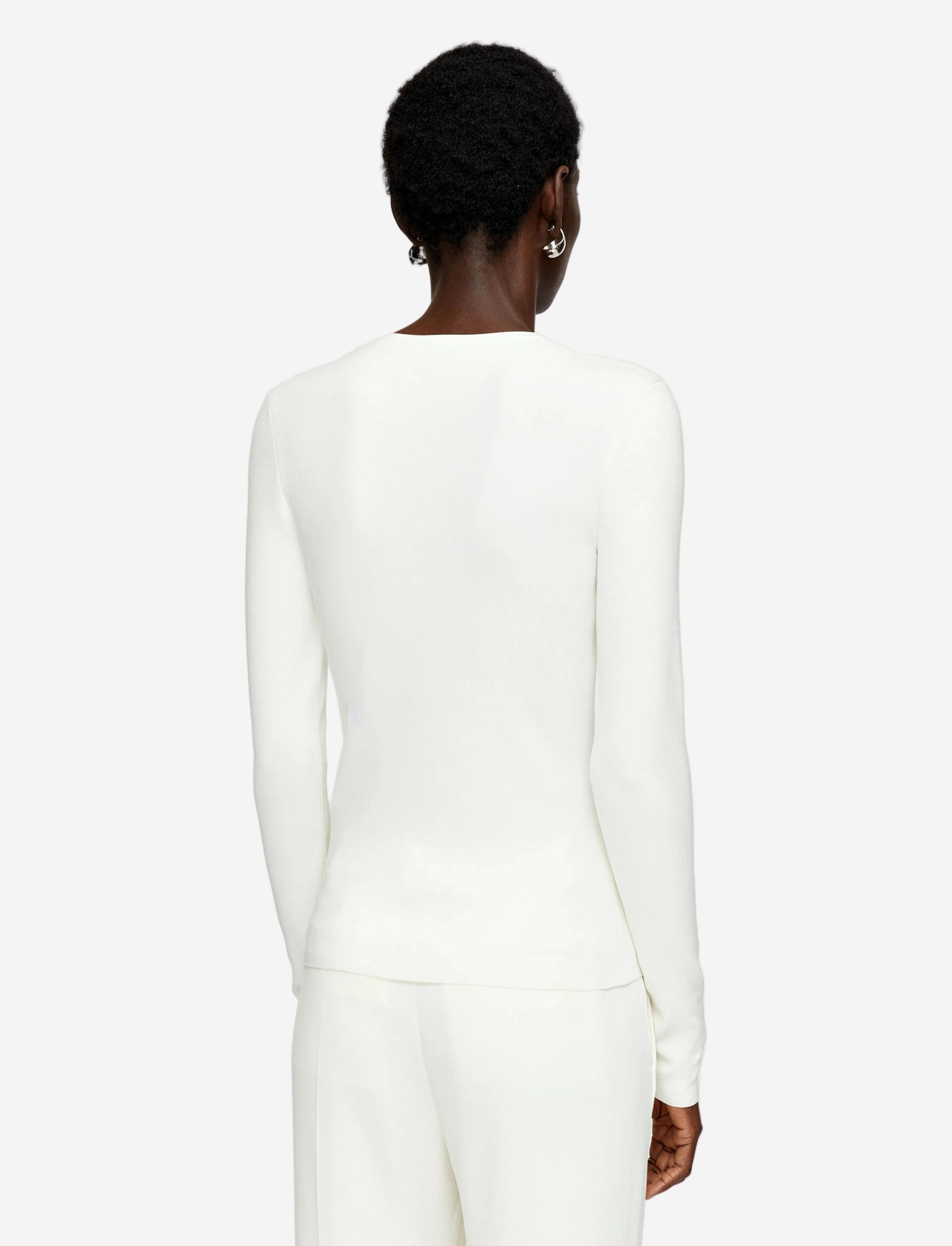 Person wearing a white long-sleeve top on a plain background