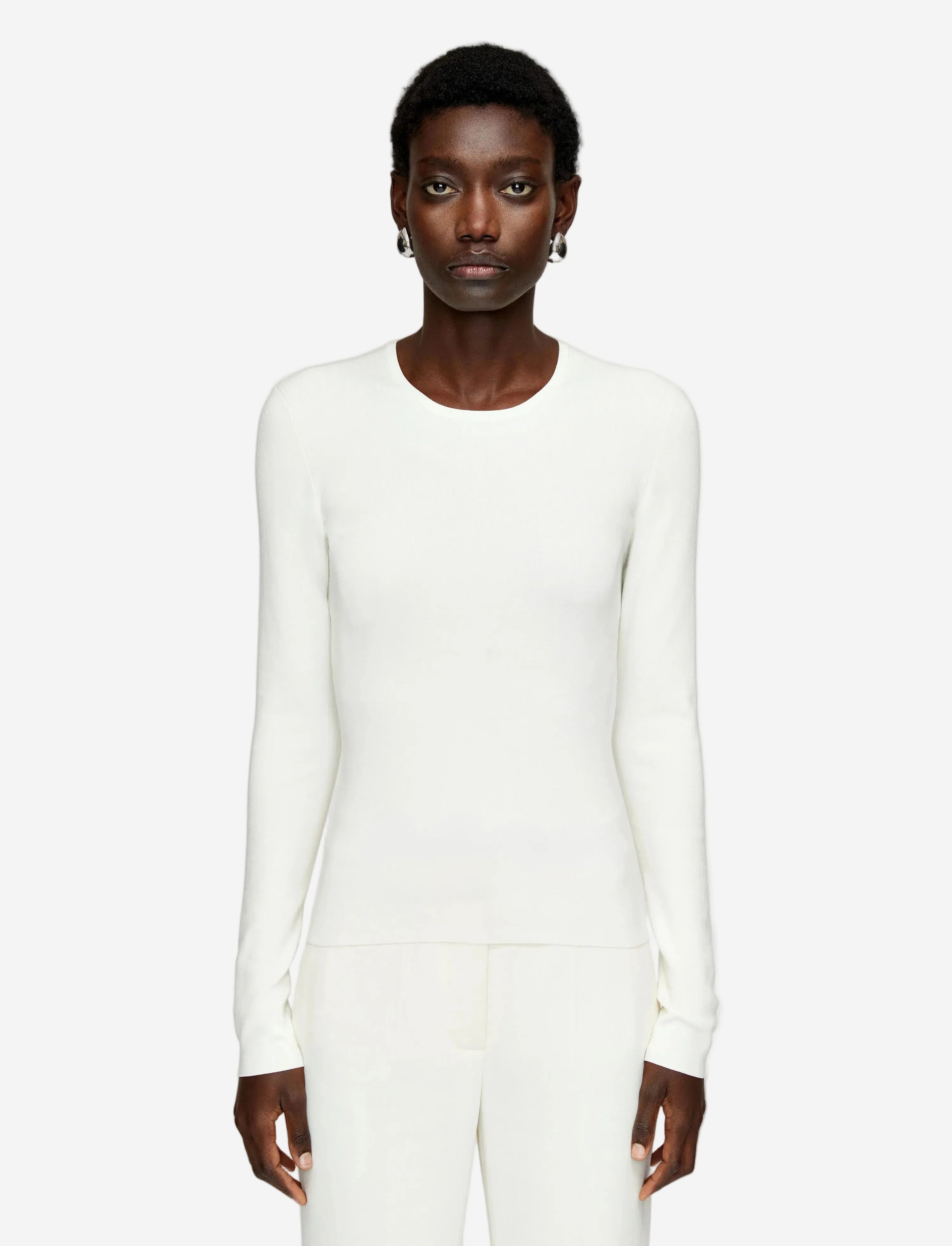 Person wearing a white long-sleeve top on a plain background