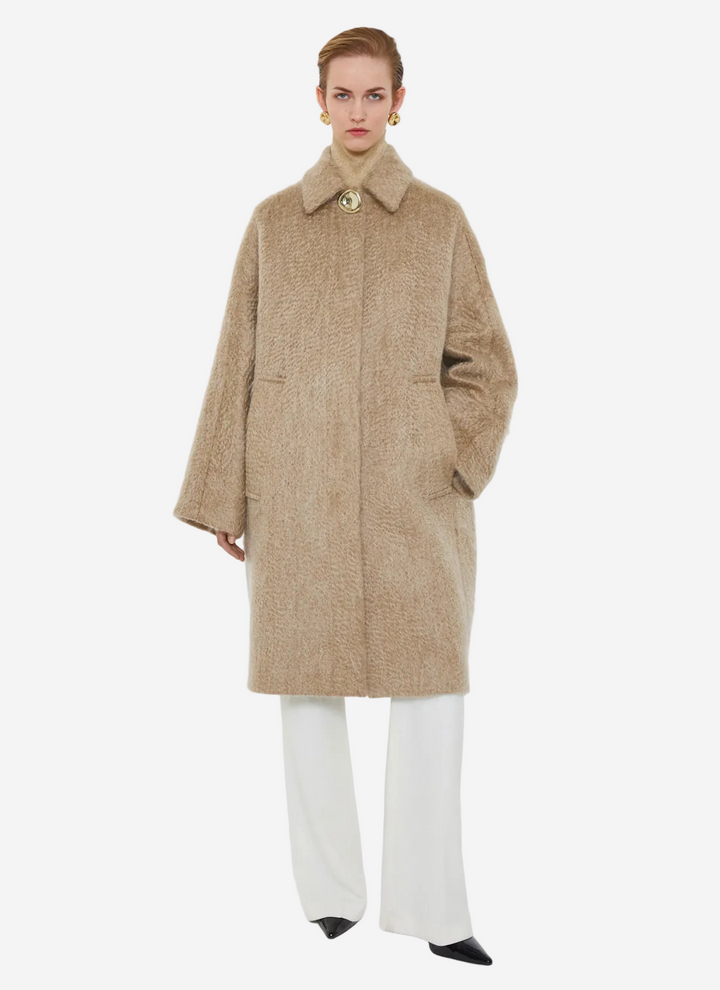 Person wearing a beige coat on a white background