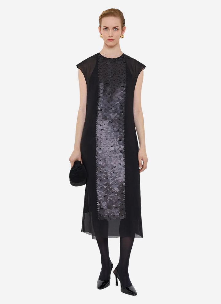 Woman wearing a black dress with a sequin panel on a white background
