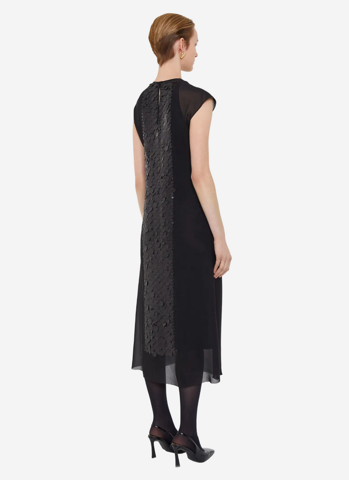 Woman wearing a black sleeveless dress with textured pattern on a white background