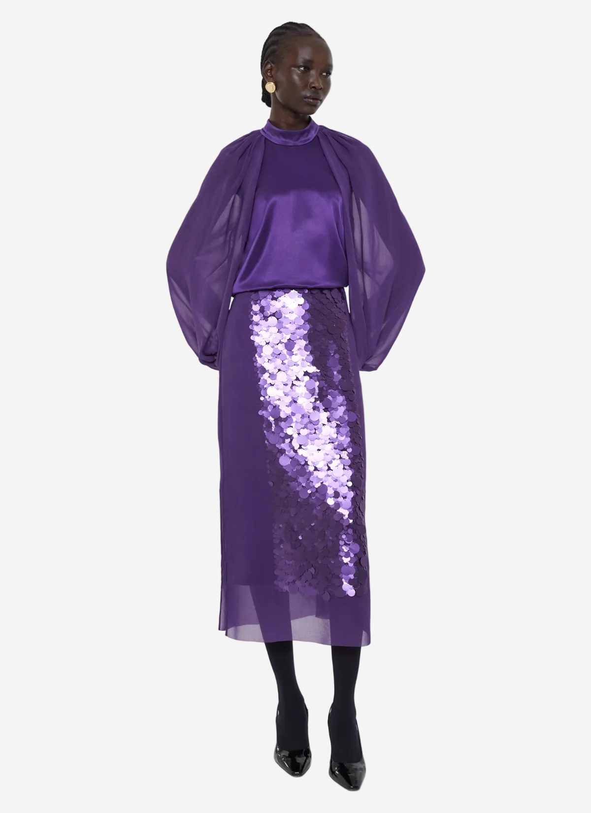 Person wearing a purple outfit with a sequin skirt on a white background