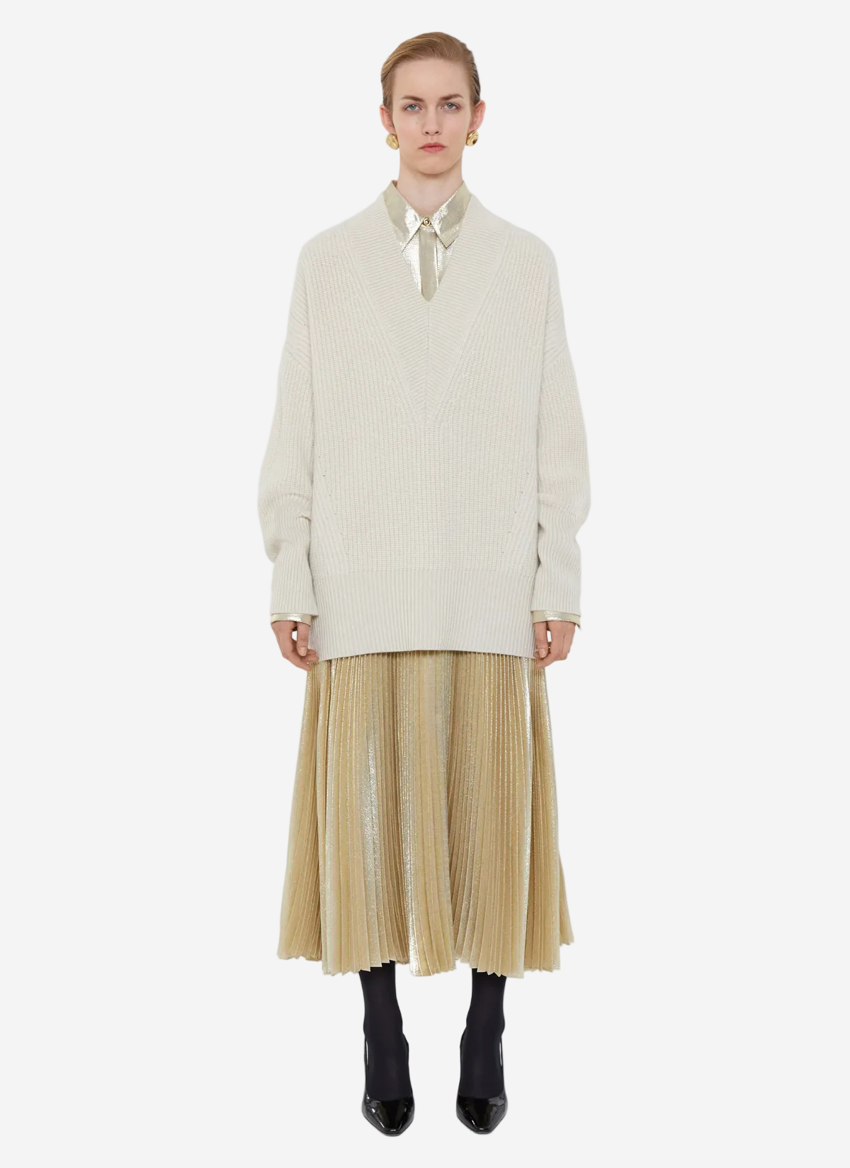 Person wearing a cream sweater and beige pleated skirt on a white background