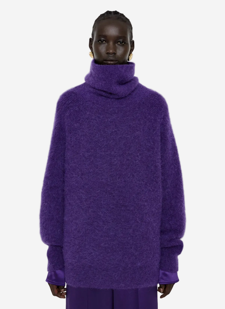 Person wearing a purple sweater on a light gray background