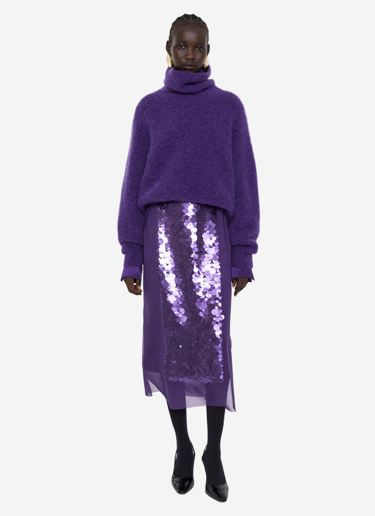 Person wearing a purple sweater and sequin skirt on a white background