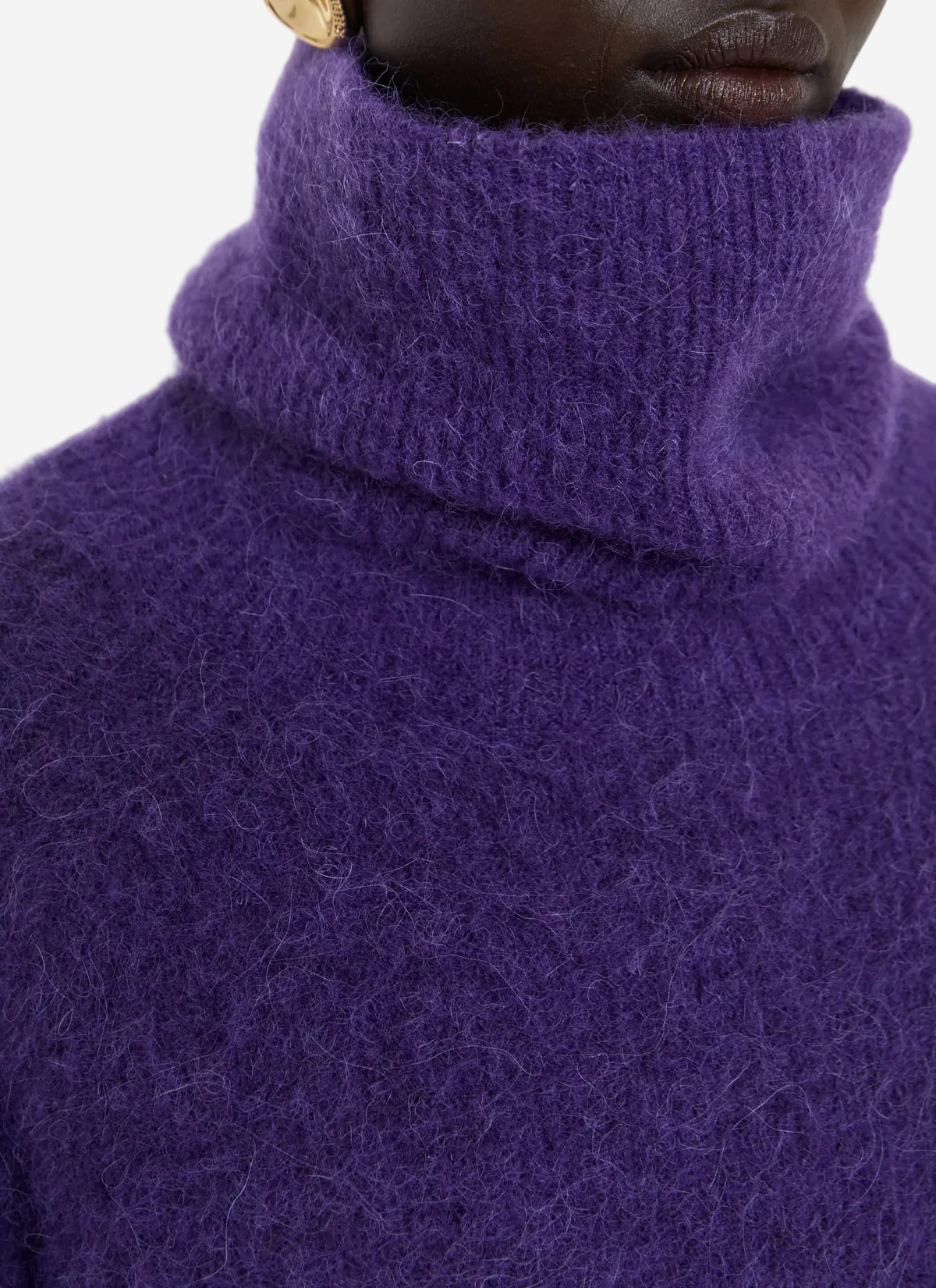 Close-up of a person wearing a purple turtleneck sweater against a white background