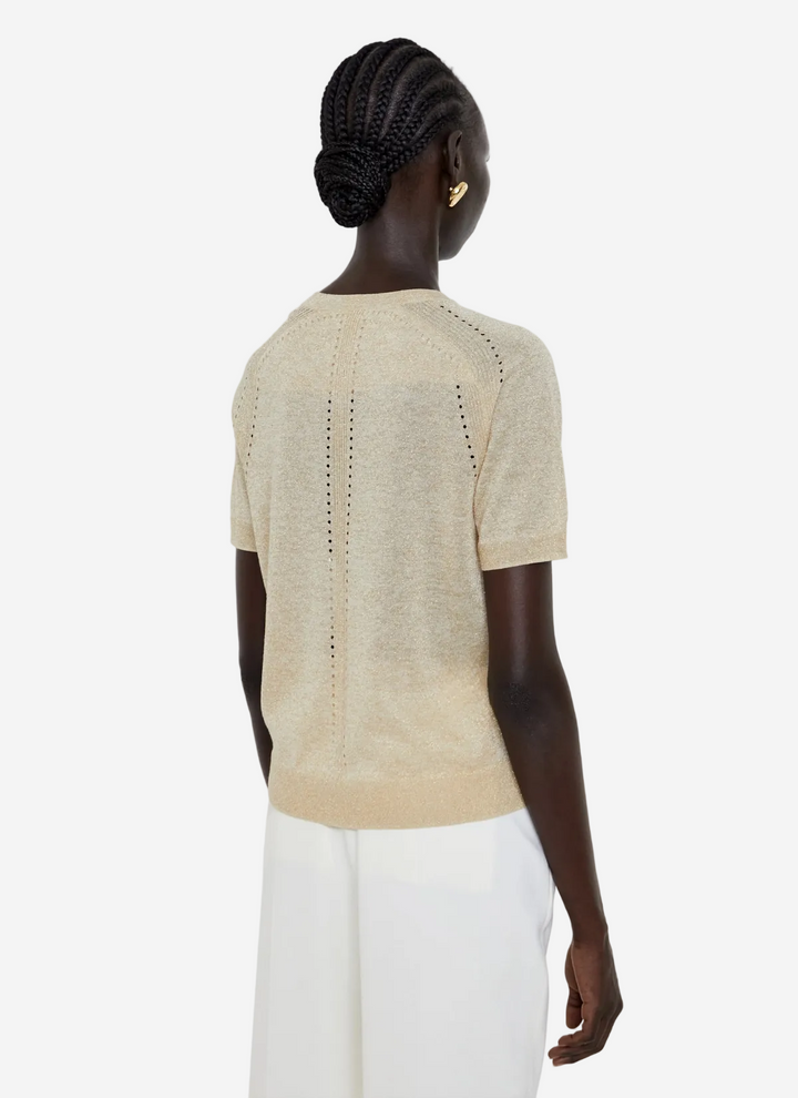 Woman wearing a beige knit top with a subtle pattern on a white background