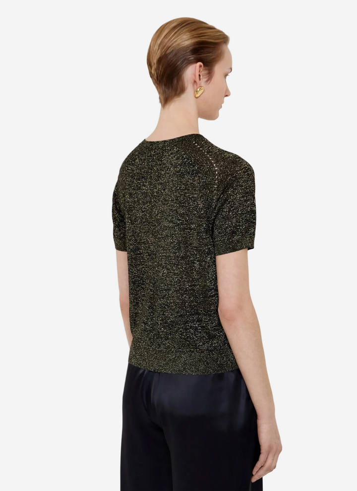 Woman wearing a green sequin top and black pants on a white background