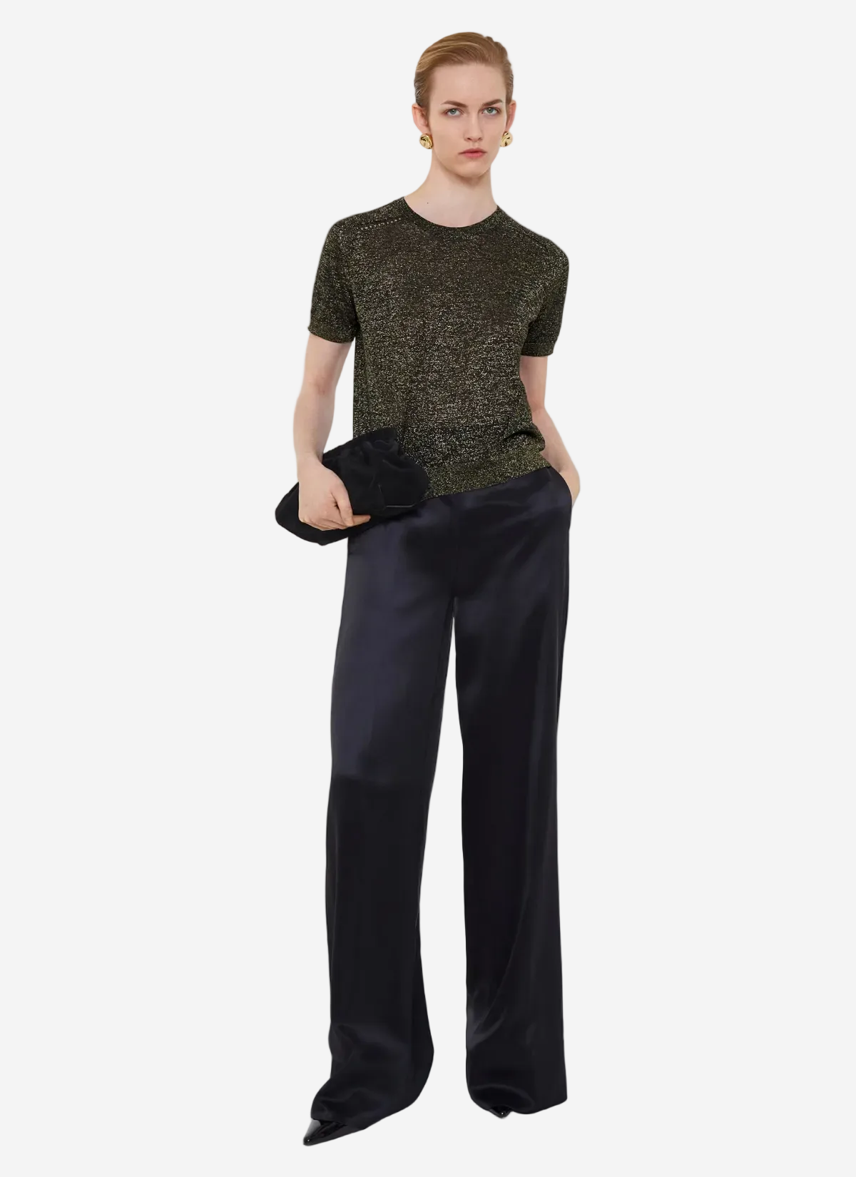 Person wearing a green patterned top and black pants on a white background