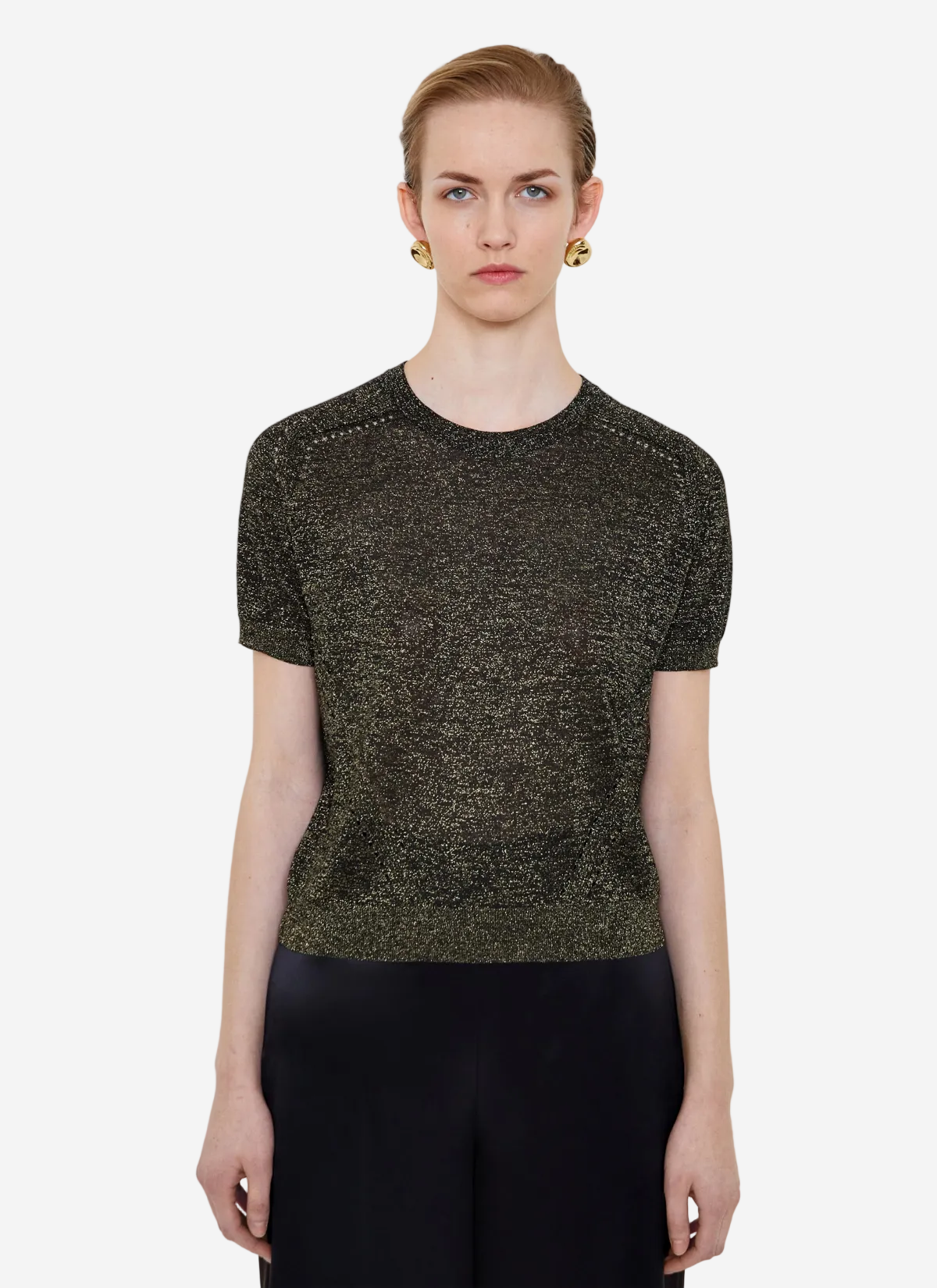 Woman wearing a textured black and gold top against a white background