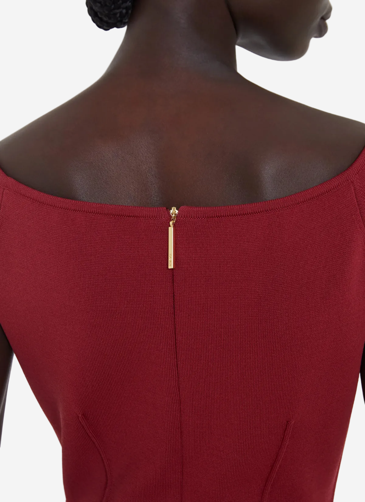 Close-up of a red dress with a gold zipper on a plain background