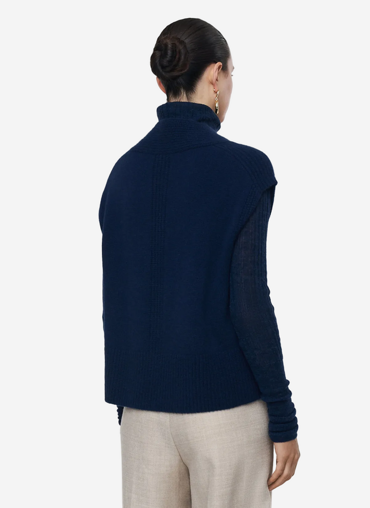 Person wearing a navy blue sweater on a light gray background