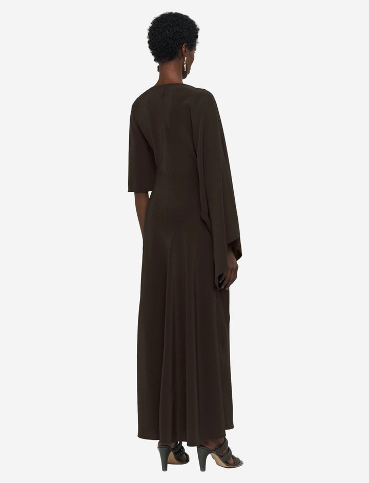 Person wearing a brown dress standing against a white background