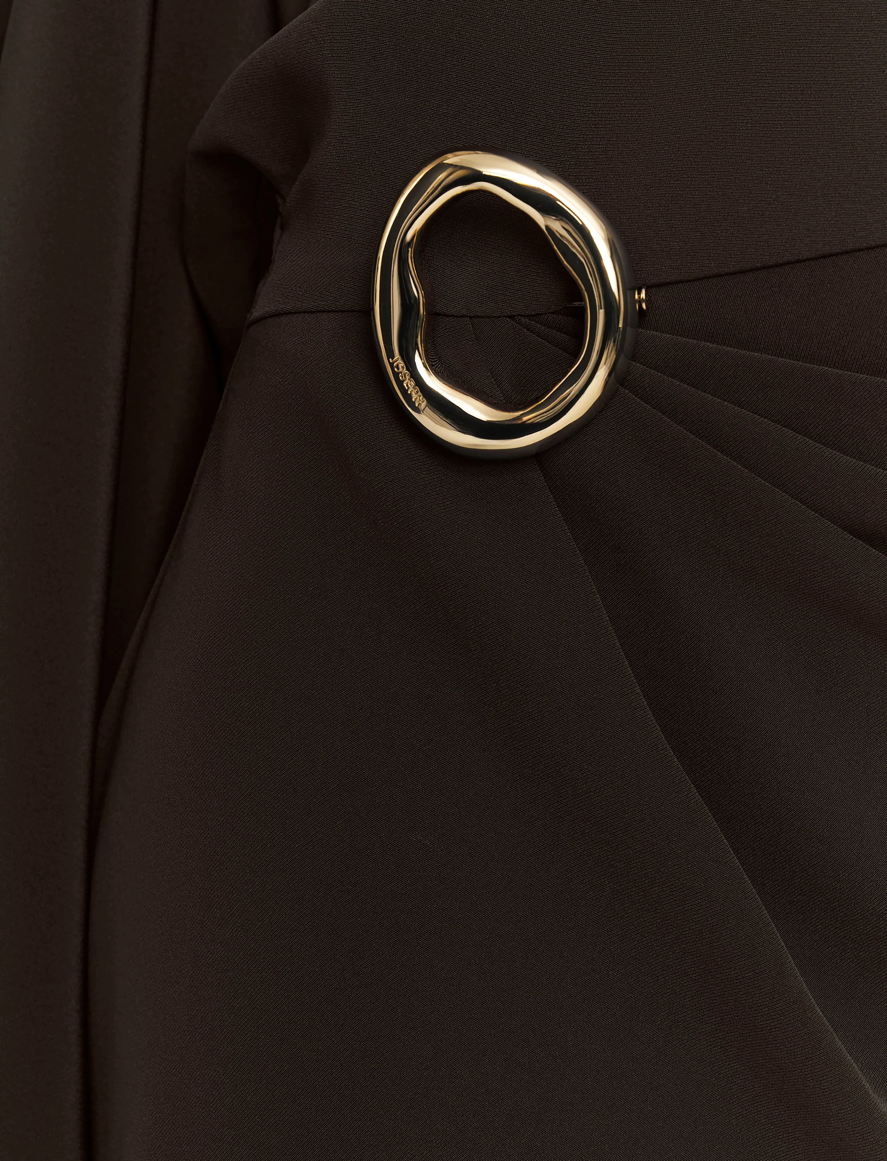 Gold circular brooch on a black fabric background