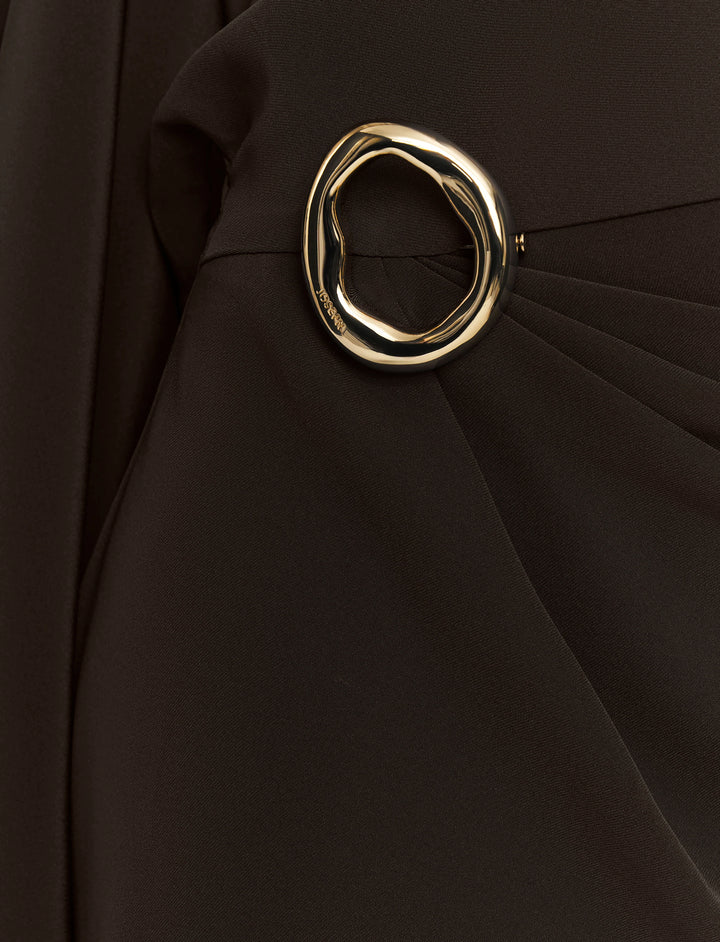 Gold circular brooch on a black fabric background
