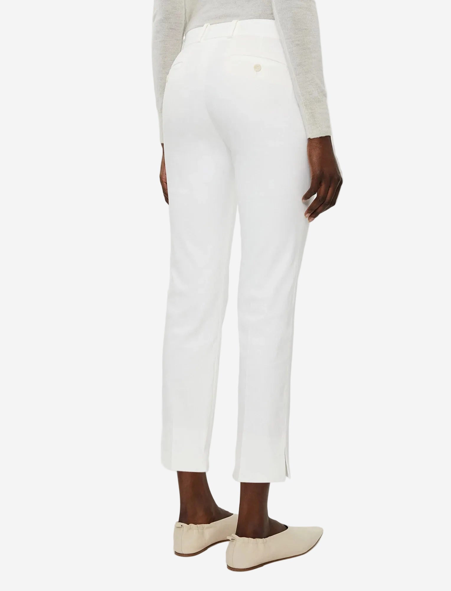 Person wearing white pants and beige shoes on a white background