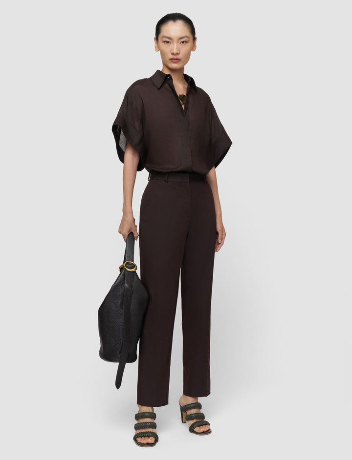 Woman wearing a brown outfit holding a black handbag on a white background