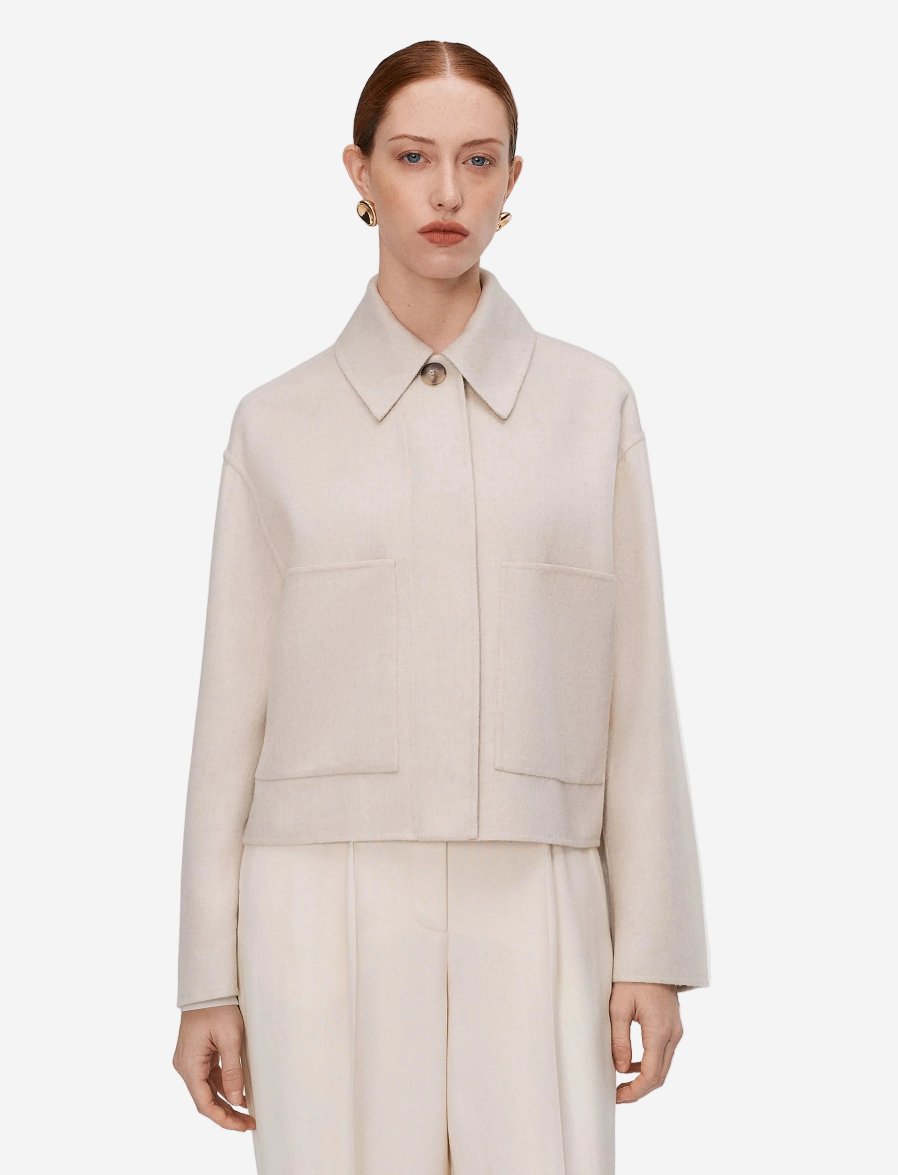 Woman wearing a beige coat and pants on a light gray background