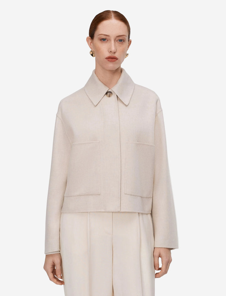 Woman wearing a beige coat and pants on a light gray background