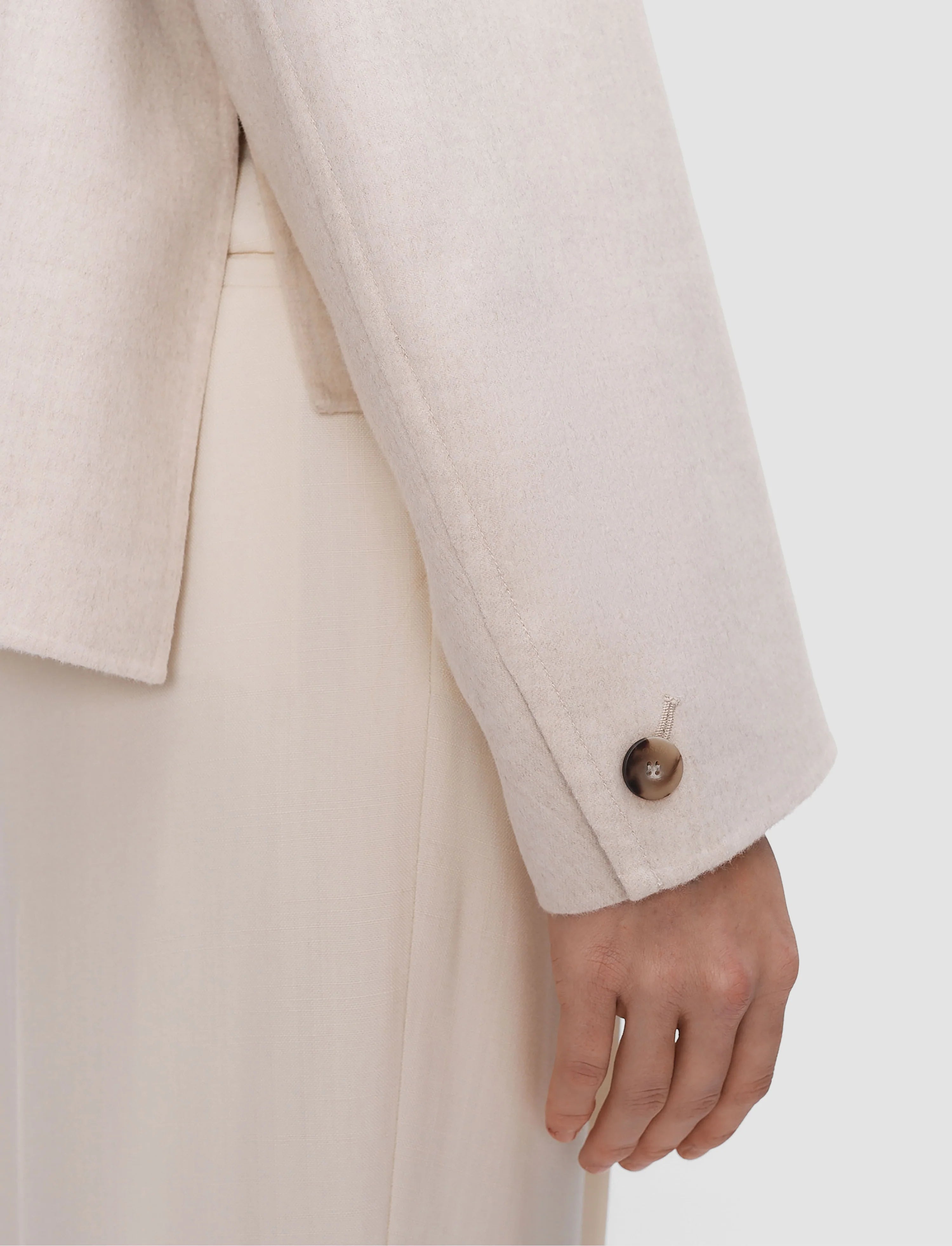 Close-up of a person wearing a beige suit with a white background