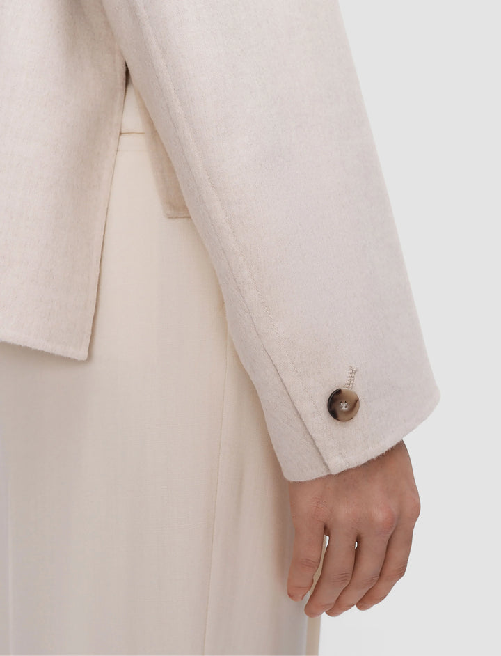 Close-up of a person wearing a beige suit with a white background