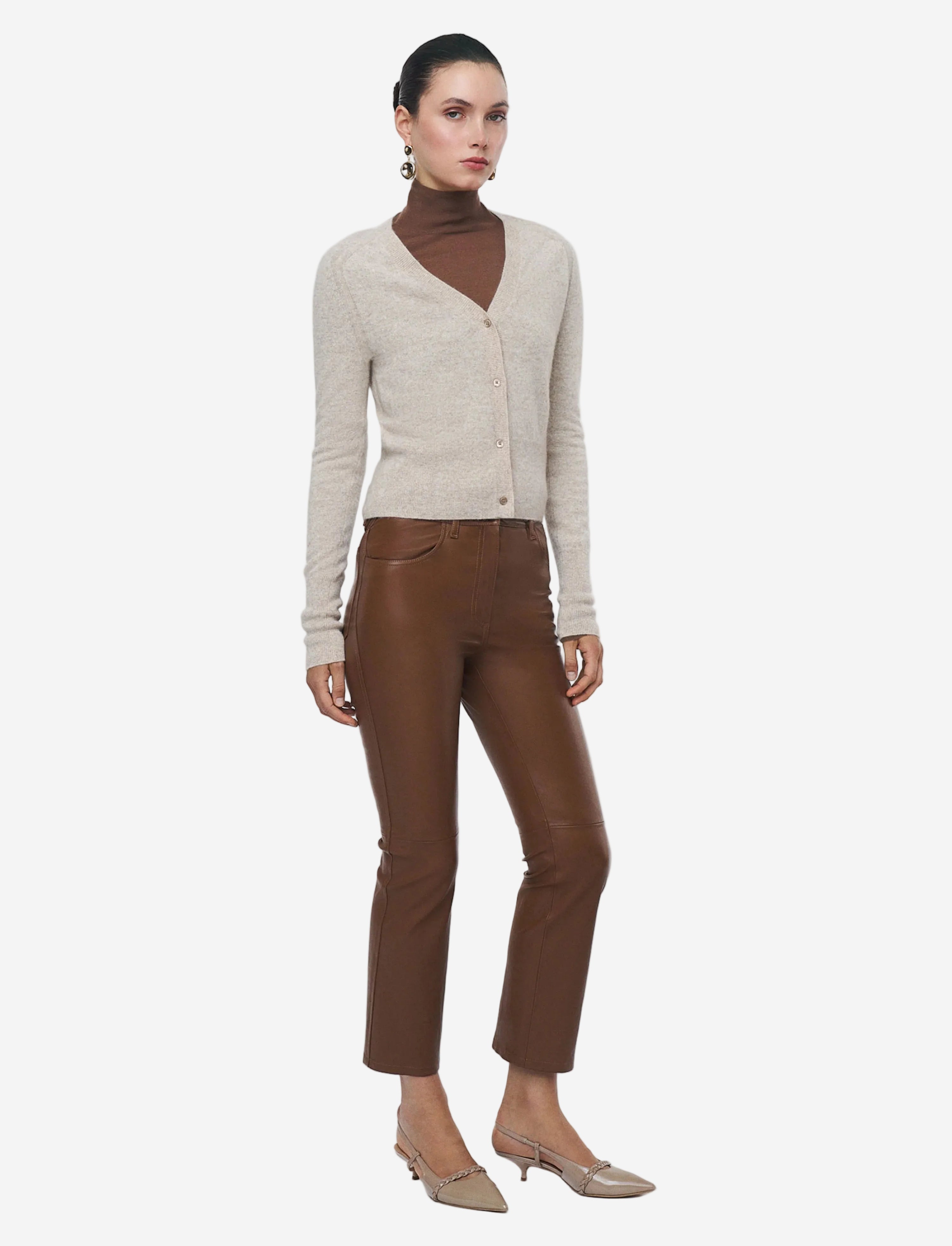 Woman wearing a beige cardigan and brown pants on a white background
